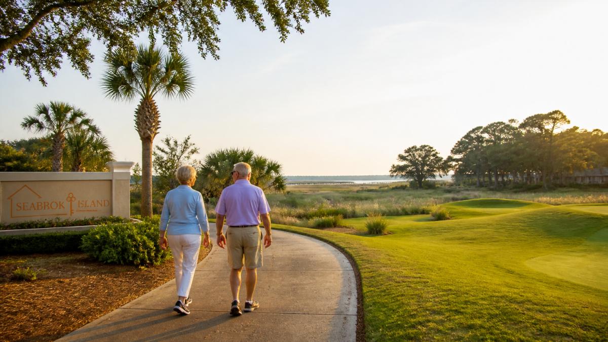 Retired couple walking a golf cart path at one of the top Charleston retirement communities near the coast.